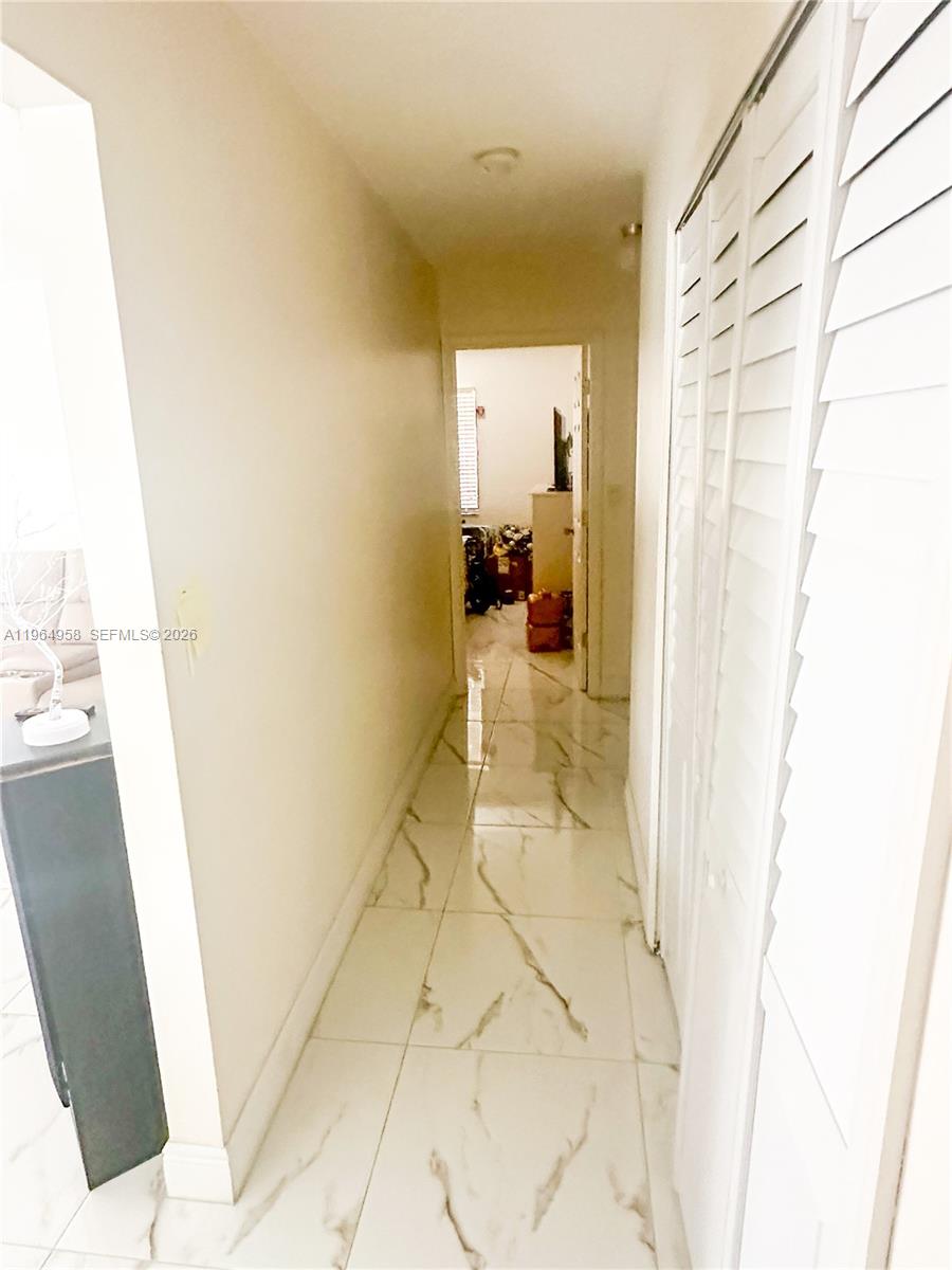 A narrow hallway features white marble-look tile flooring and white louvered closet doors — 14759 SW 82nd St, Miami FL 33193, MIAMI, FL