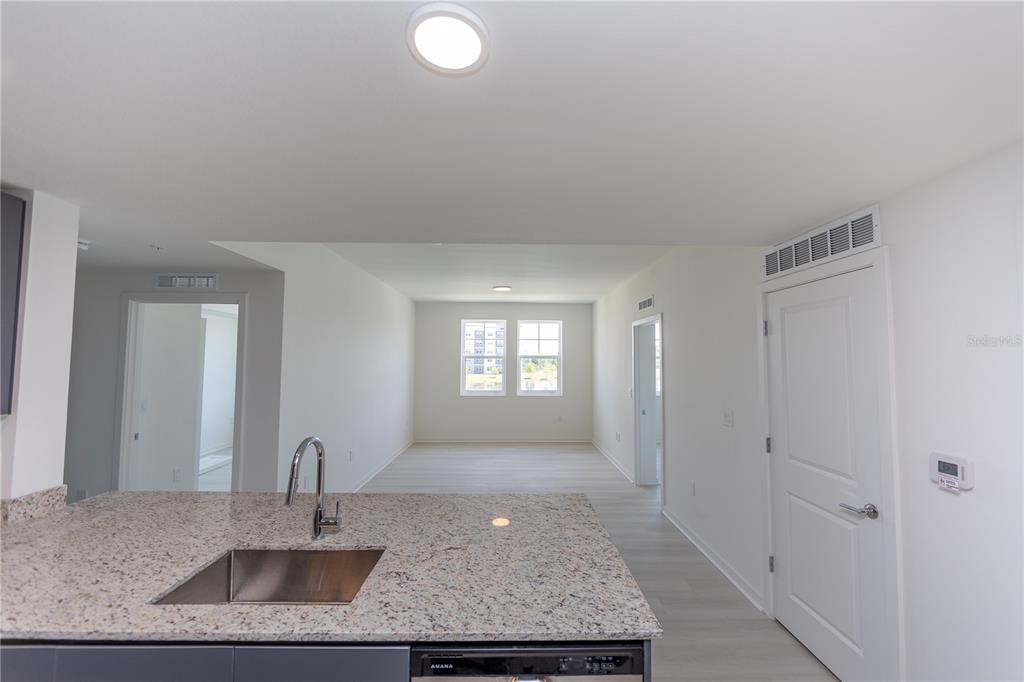 A kitchen island with a granite countertop and sink overlooks an open living area — 5579 MILLENIA PARK BLVD UNIT 209, ORLANDO, FL
