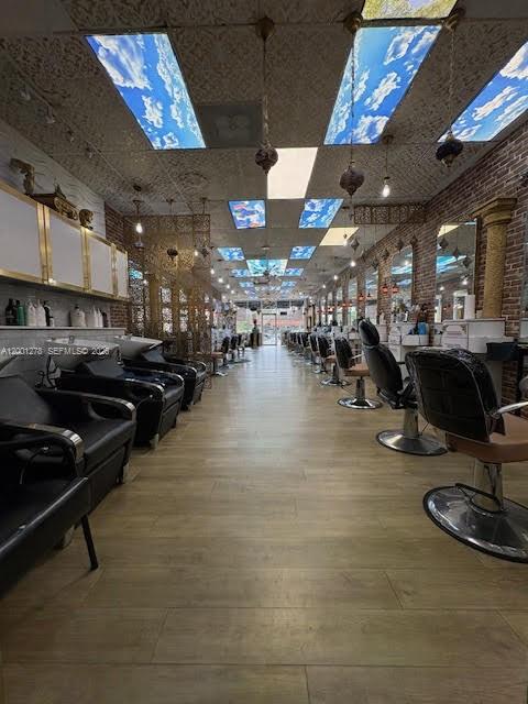 A hair salon features rows of styling chairs, wood-look flooring, and a sky-patterned drop ceiling — FL-7, Boca Raton FL 33428, BOCA RATON, FL