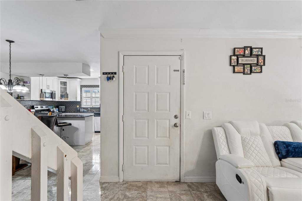 A white front door sits between a staircase, a kitchen, and a white sofa — 12742 WOOD TRAIL BLVD BOULEVARD, TAMPA, FL