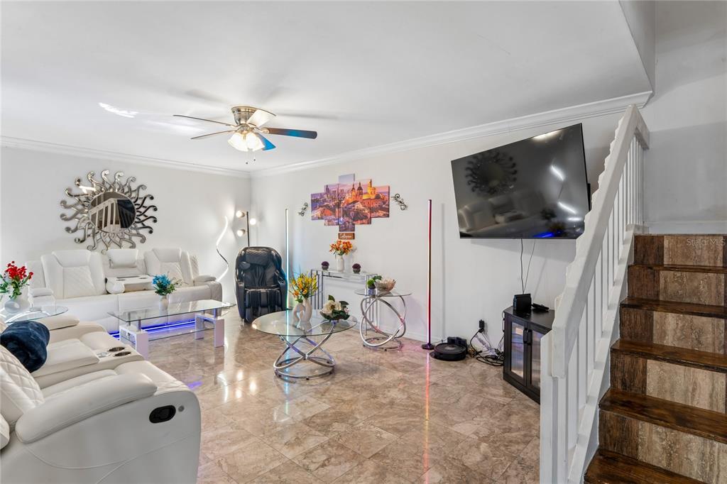 A living room features white leather sofas, a glass coffee table, and stairs with wood treads — 12742 WOOD TRAIL BLVD BOULEVARD, TAMPA, FL