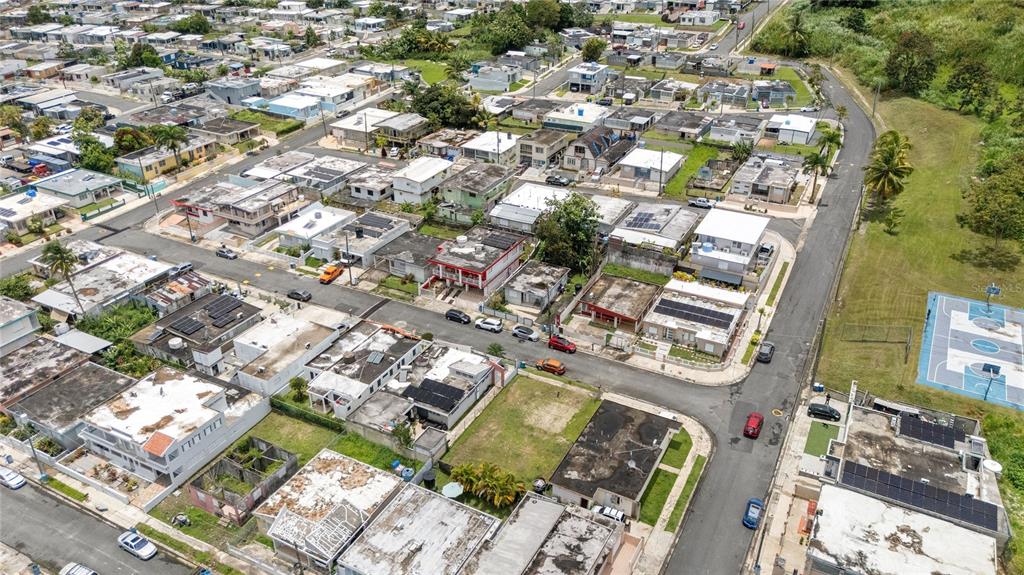 An aerial view shows a dense residential neighborhood with flat-roofed houses and a basketball court — CII JOSE CAMPECHE, LAS PIEDRAS, PR