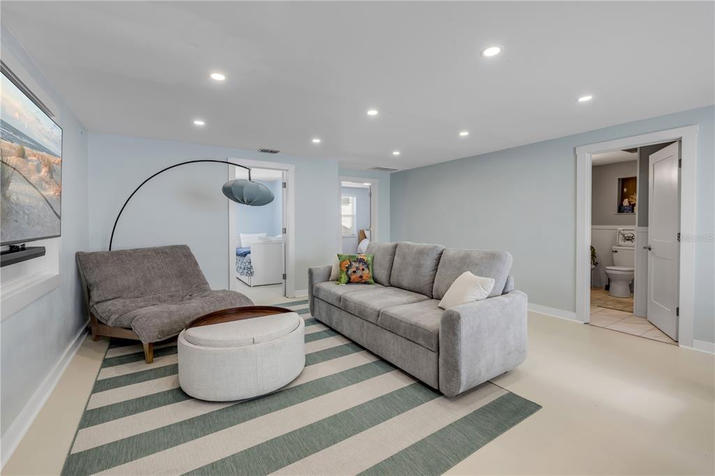 A living room features a gray sofa, a lounge chair, and a striped area rug — 308 DUE EAST STREET, NEW SMYRNA BEACH, FL