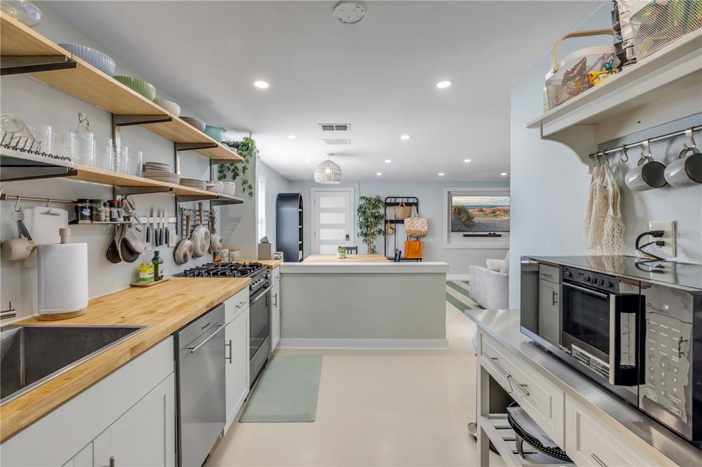 A kitchen with light gray cabinets, wood countertops, open shelving, and a stainless steel microwave — 308 DUE EAST STREET, NEW SMYRNA BEACH, FL