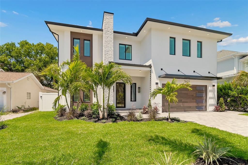 A modern two-story house with white stucco, wood accents, a stone chimney, and a garage — 3605 W KENSINGTON AVENUE, TAMPA, FL