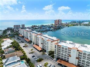 An aerial view shows a multi-story waterfront apartment complex with a parking lot and pool — 17735 GULF BOULEVARD UNIT 204, REDINGTON SHORES, FL