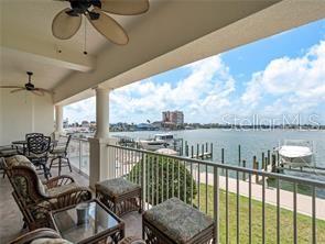 A covered balcony with outdoor furniture overlooks a bay with boat docks and a building — 17735 GULF BOULEVARD UNIT 204, REDINGTON SHORES, FL