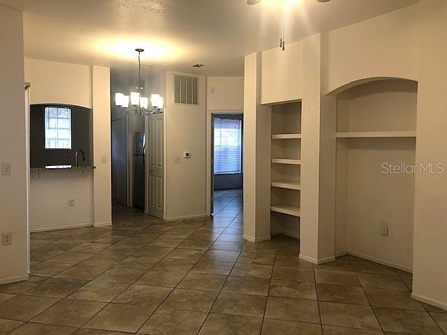 A room with tile flooring, a chandelier, built-in shelving, and a view into the kitchen — 102 VISTA VERDI CIRCLE UNIT 112, LAKE MARY, FL