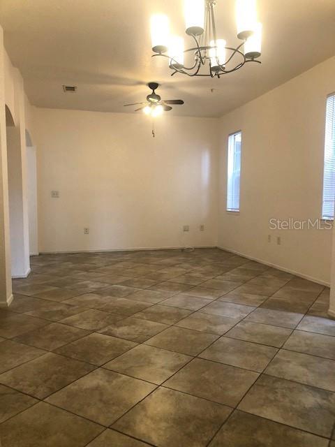 An empty room features beige tile flooring, a ceiling fan, and a hanging chandelier — 102 VISTA VERDI CIRCLE UNIT 112, LAKE MARY, FL