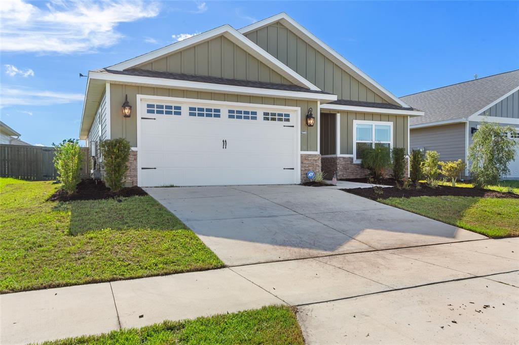 A single-story house with olive green siding, a two-car garage, and a concrete driveway — 1689 SW 71ST CIRCLE, GAINESVILLE, FL