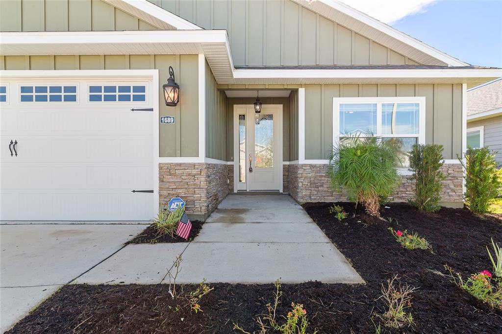 The exterior of a house features green vertical siding, stone veneer, and a white door — 1689 SW 71ST CIRCLE, GAINESVILLE, FL