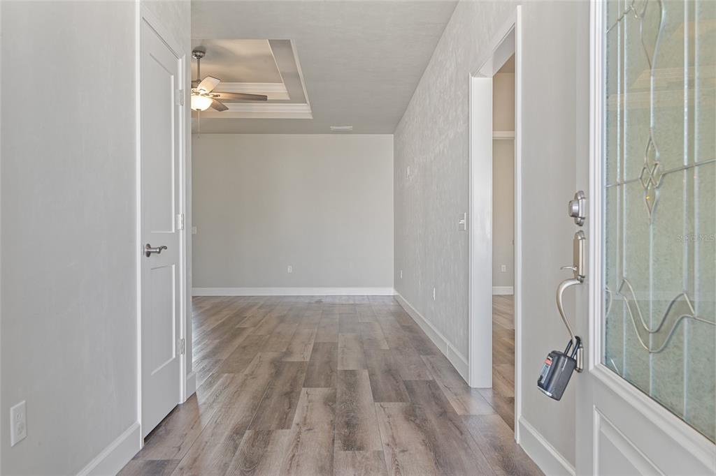An entryway with wood-look flooring leads to a living area featuring a tray ceiling — 1689 SW 71ST CIRCLE, GAINESVILLE, FL