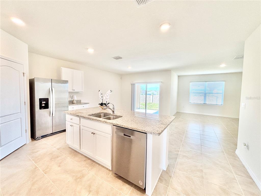 A kitchen with white cabinets, granite countertops, stainless steel appliances, and tile flooring — 2752 GENTLE RAIN DRIVE, DAVENPORT, FL