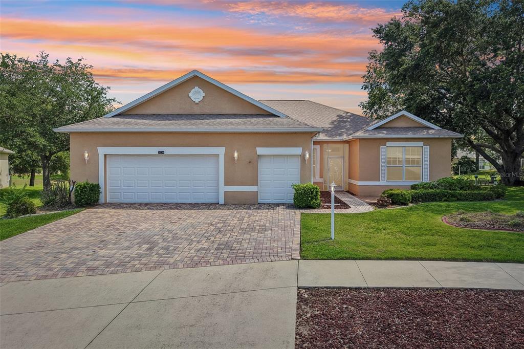 A single-story house with a tan stucco exterior, a three-car garage, and a paved driveway — 3538 MULBERRY GROVE LOOP, LEESBURG, FL