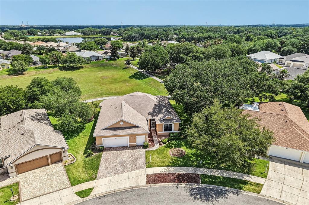 An aerial view of a suburban house with a paved driveway and surrounding green landscape — 3538 MULBERRY GROVE LOOP, LEESBURG, FL