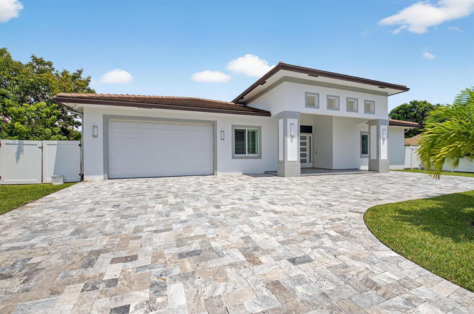 A single-story house with a white exterior, a paved driveway, and a two-car garage — 711 NE 6th Street, Boca Raton FL 33432, BOCA RATON, FL