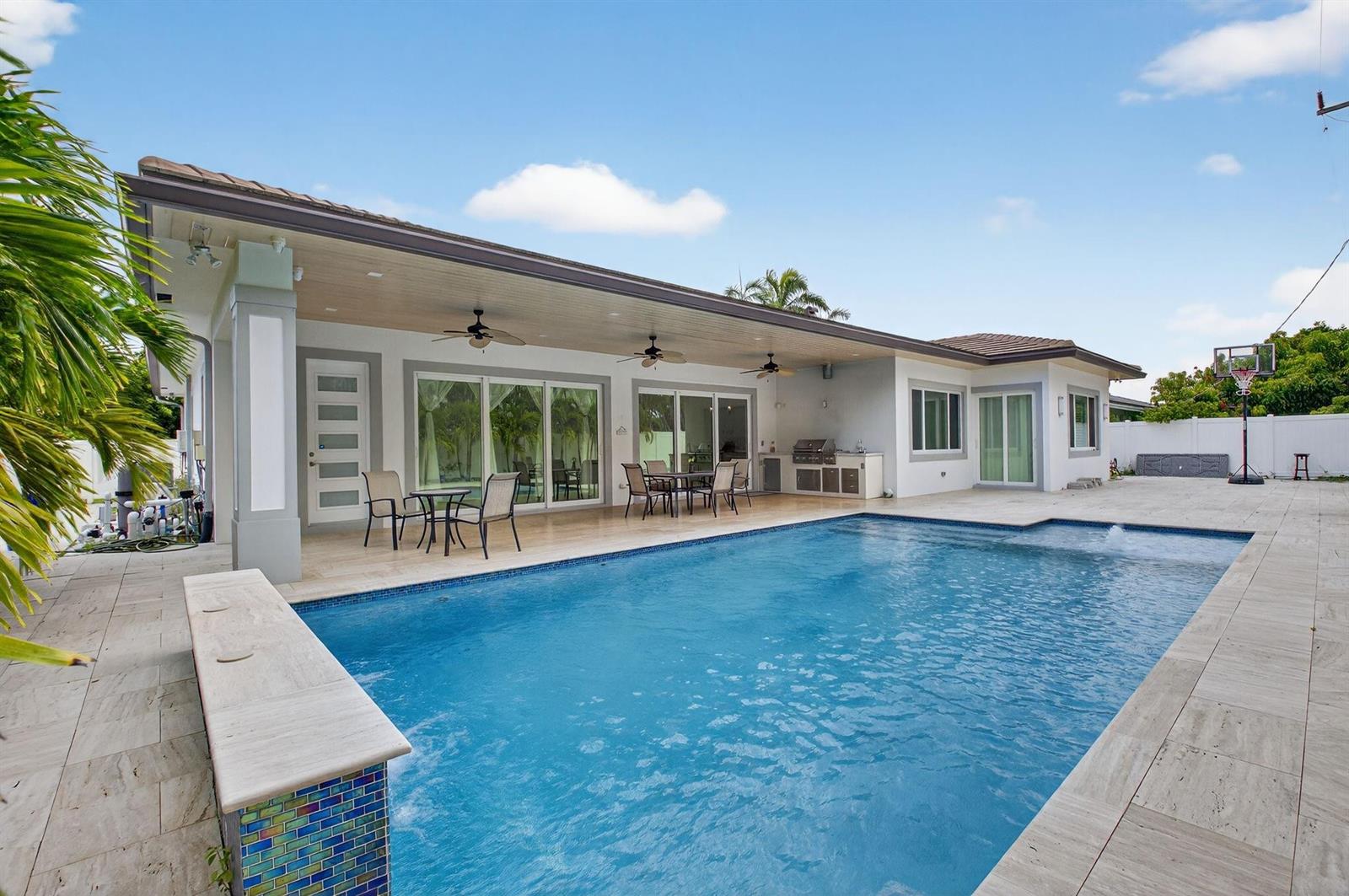 A backyard features a swimming pool, a covered patio with ceiling fans, and a grill station — 711 NE 6th Street, Boca Raton FL 33432, BOCA RATON, FL