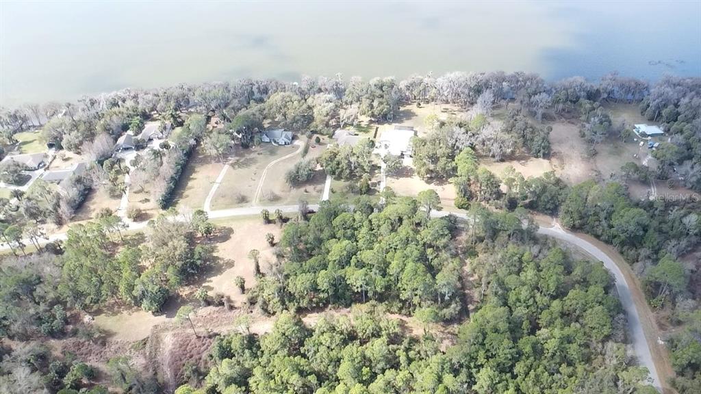 An aerial view shows several houses situated along a lakefront surrounded by dense trees — 13837 SE 201ST TERRACE, HAWTHORNE, FL