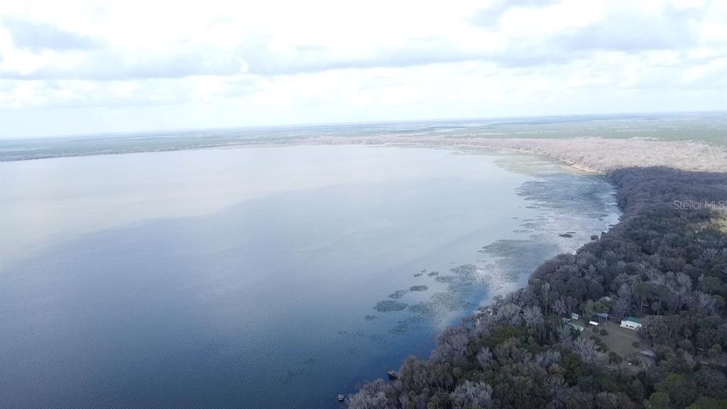 An aerial view shows a large lake bordered by a dense forest and some buildings — 13837 SE 201ST TERRACE, HAWTHORNE, FL