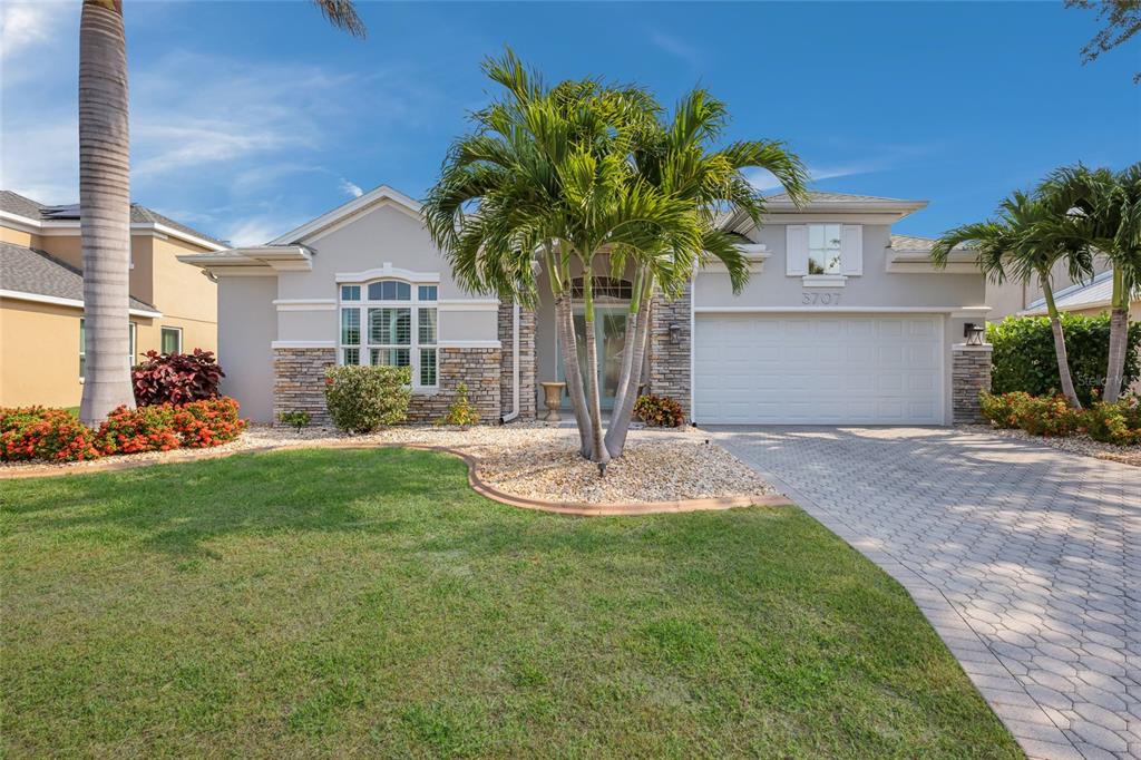 A single-story house with a stone facade, a paved driveway, and palm trees in front — 3707 5TH AVENUE NE, BRADENTON, FL