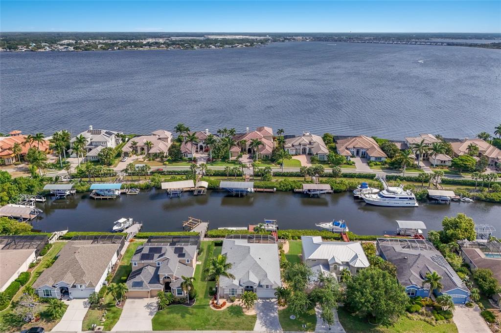 An aerial view shows waterfront homes with private boat docks along a canal and river — 3707 5TH AVENUE NE, BRADENTON, FL