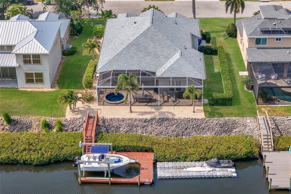 An aerial view of a waterfront house with a screened pool, dock, and boat lift — 3707 5TH AVENUE NE, BRADENTON, FL
