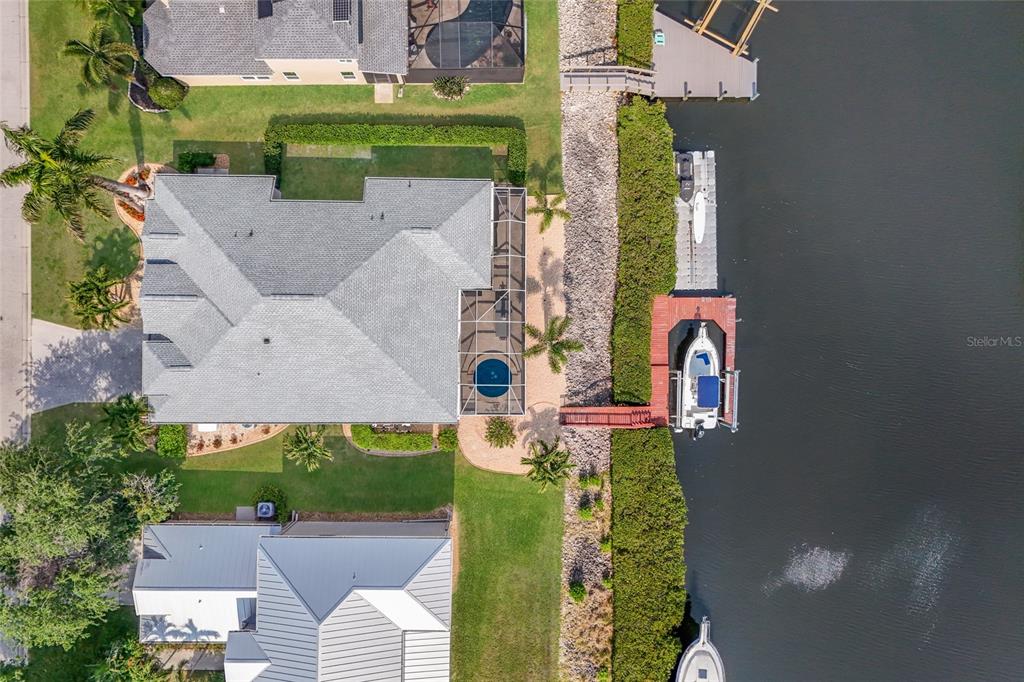 An aerial view shows a waterfront house with a pool, dock, and boat — 3707 5TH AVENUE NE, BRADENTON, FL
