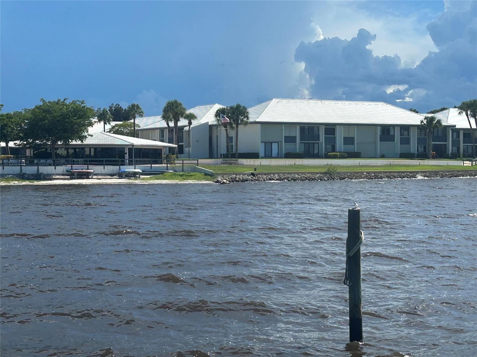 A view of a waterfront apartment complex with a white roof and palm trees — 175 SE Saint Lucie Boulevard # E134, Stuart FL 34996, STUART, FL