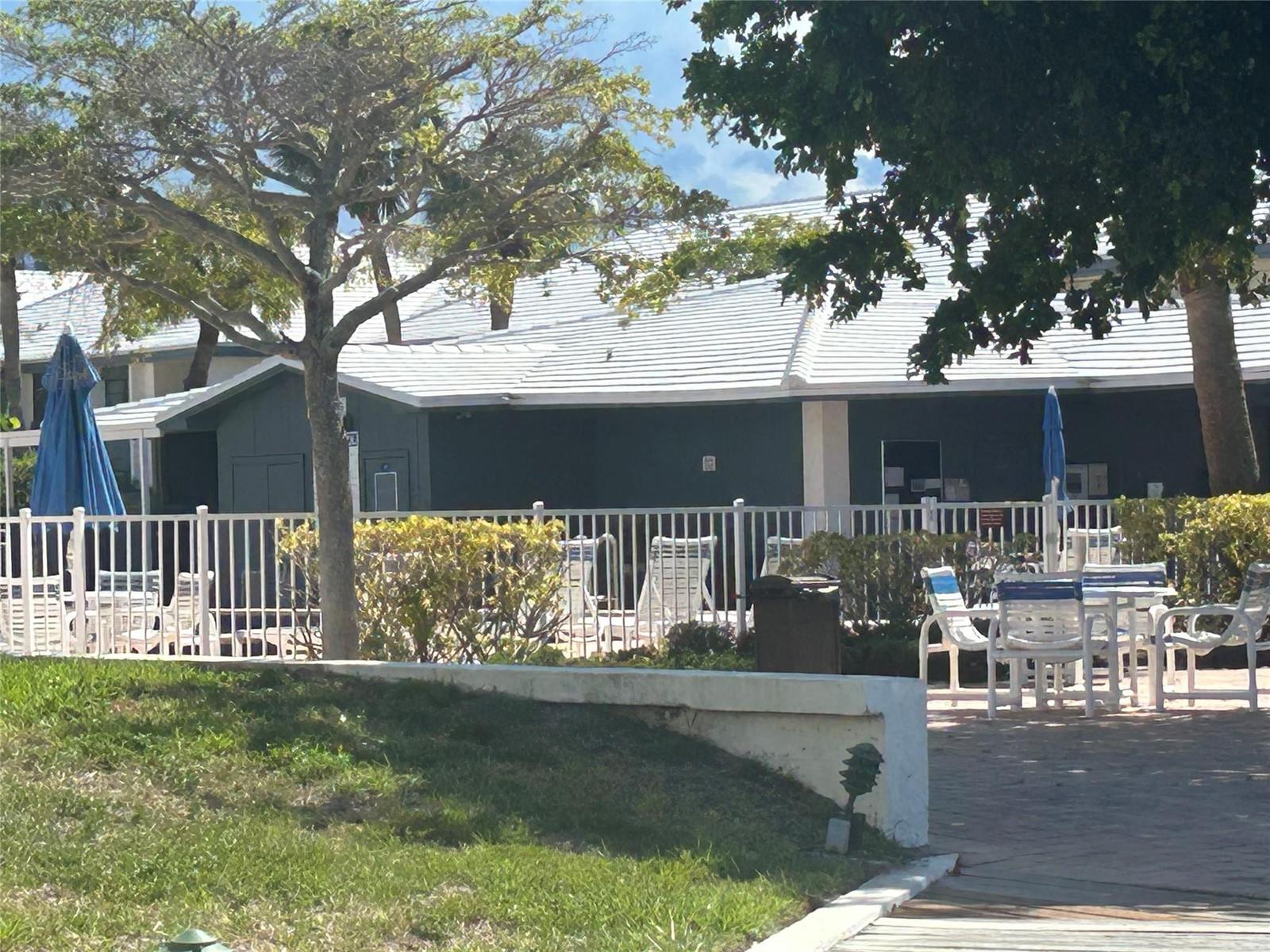 A white fence surrounds a patio area with outdoor furniture and a dark building — 175 SE Saint Lucie Boulevard # E134, Stuart FL 34996, STUART, FL