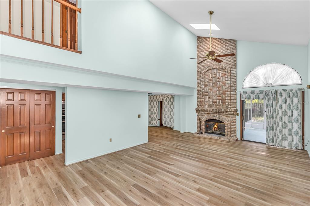 A living room with light blue walls, wood flooring, a brick fireplace, and a loft — 5412 RUTLAND COURT, ORLANDO, FL