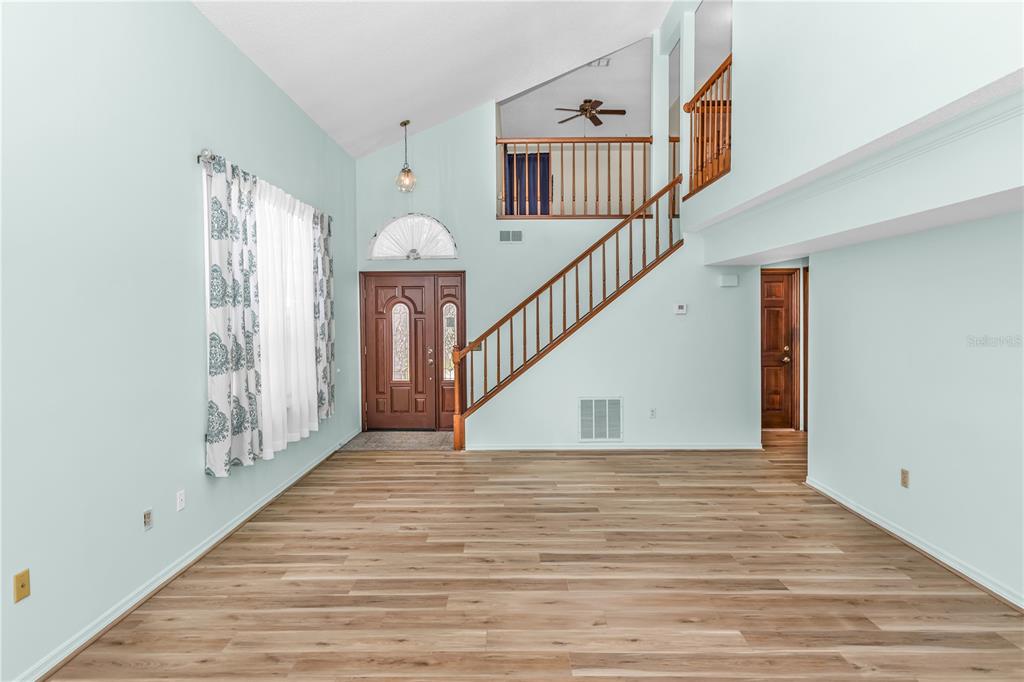 An entryway with light blue walls, wood-look flooring, a staircase, and a front door — 5412 RUTLAND COURT, ORLANDO, FL
