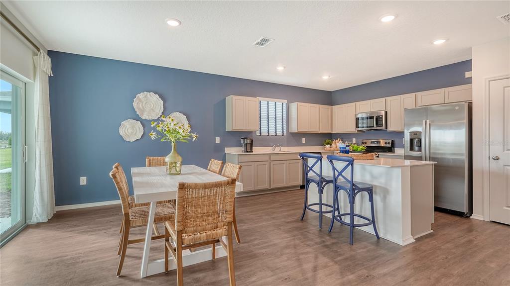 A kitchen and dining area with blue walls, light wood cabinets, and a kitchen island — 12927 RED DEER PLACE, PARRISH, FL