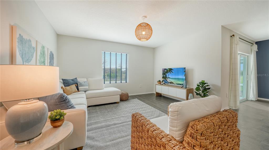 A living room features a white sectional sofa, a woven armchair, and a television console — 12927 RED DEER PLACE, PARRISH, FL