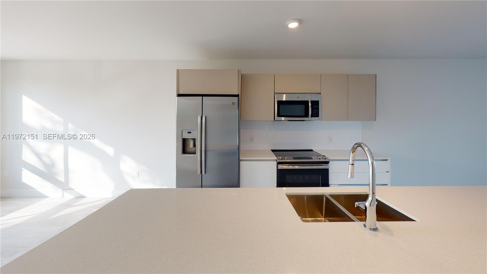 A modern kitchen features stainless steel appliances, white cabinetry, and a large quartz island — 2555 NE 193rd St # 2224, Miami FL 33180, MIAMI, FL