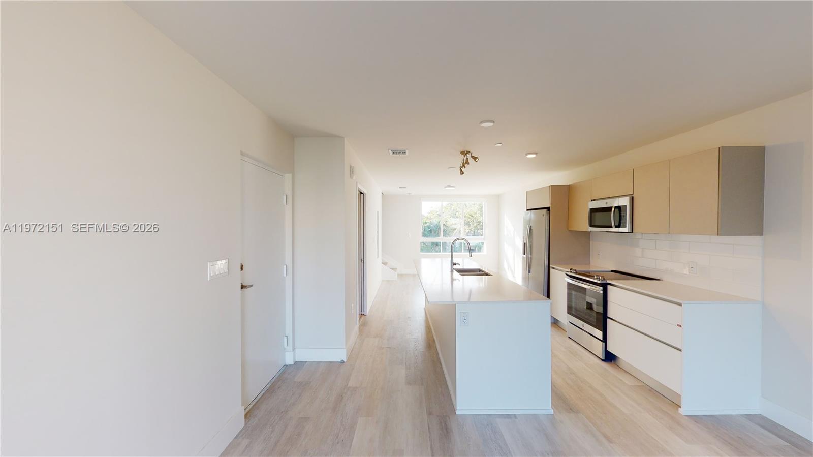 A modern kitchen features a white island, light wood cabinets, and stainless steel appliances — 2555 NE 193rd St # 2224, Miami FL 33180, MIAMI, FL