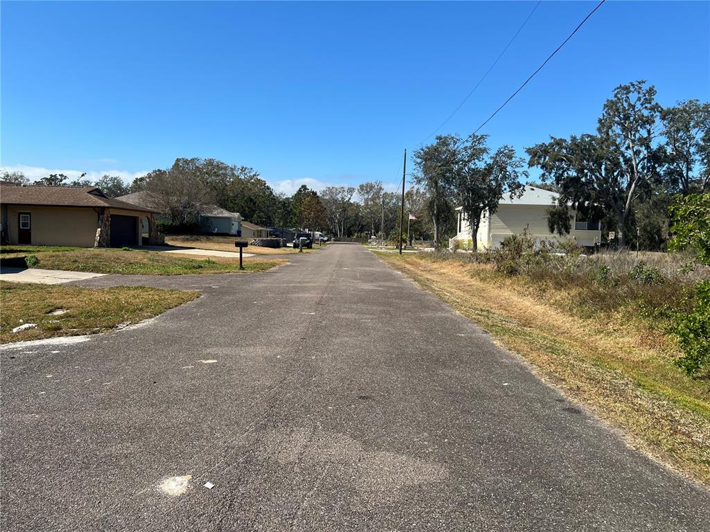 A paved residential street lined with houses, trees, and utility poles under a clear sky — 4715 SALVIA STREET, NEW PORT RICHEY, FL