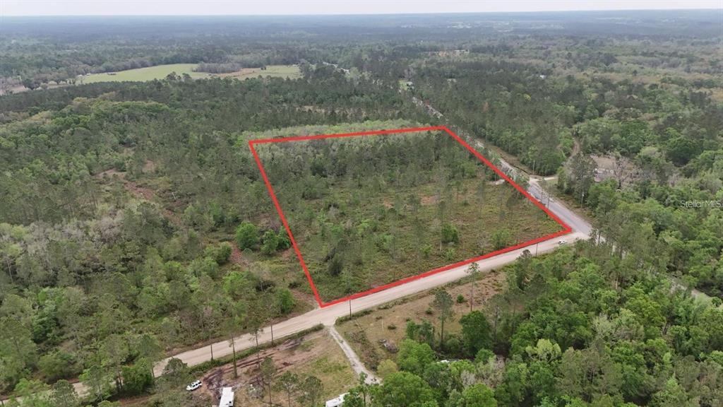 An aerial view shows a rectangular plot of land outlined in red beside a road — SE COUNTY ROAD 25A, WHITE SPRINGS, FL