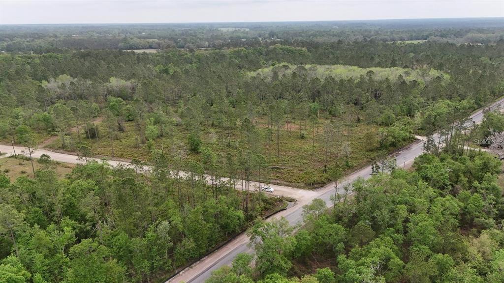 An aerial view shows a wooded lot at the intersection of two rural roads — SE COUNTY ROAD 25A, WHITE SPRINGS, FL