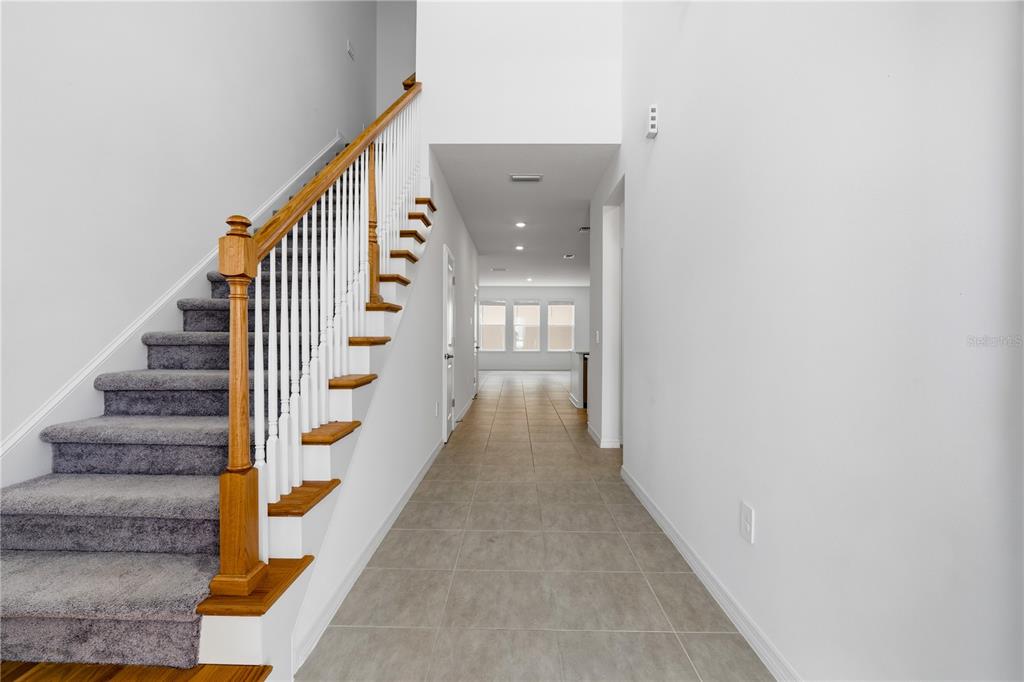 A staircase with gray carpet and a wooden railing leads to a tiled hallway — 15010 SUMMER HARVEST STREET, WINTER GARDEN, FL