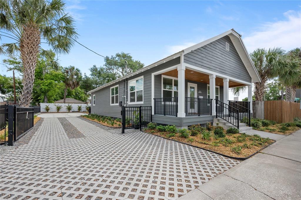 A gray house with a front porch and a permeable paver driveway sits outdoors — 2203 N BOULEVARD, TAMPA, FL