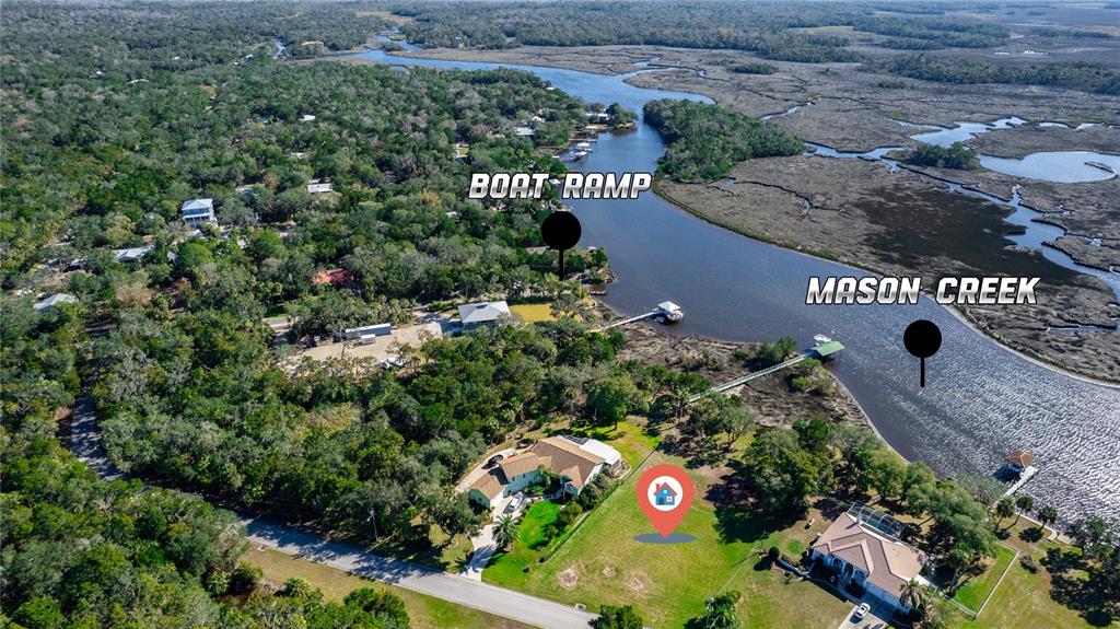 This aerial view shows a waterfront property with a house, lawn, and nearby boat ramp — 12214 W RESTVIEW COURT, HOMOSASSA, FL