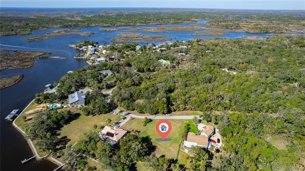 An aerial view shows a vacant residential lot situated between two houses near a waterway — 12214 W RESTVIEW COURT, HOMOSASSA, FL