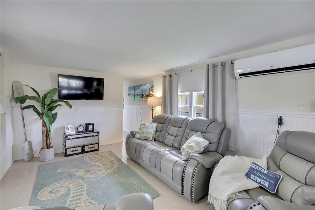 A living room features a grey sofa, a wall-mounted television, and a seahorse-patterned area rug — 2630 N COMANCHE POINT, CRYSTAL RIVER, FL