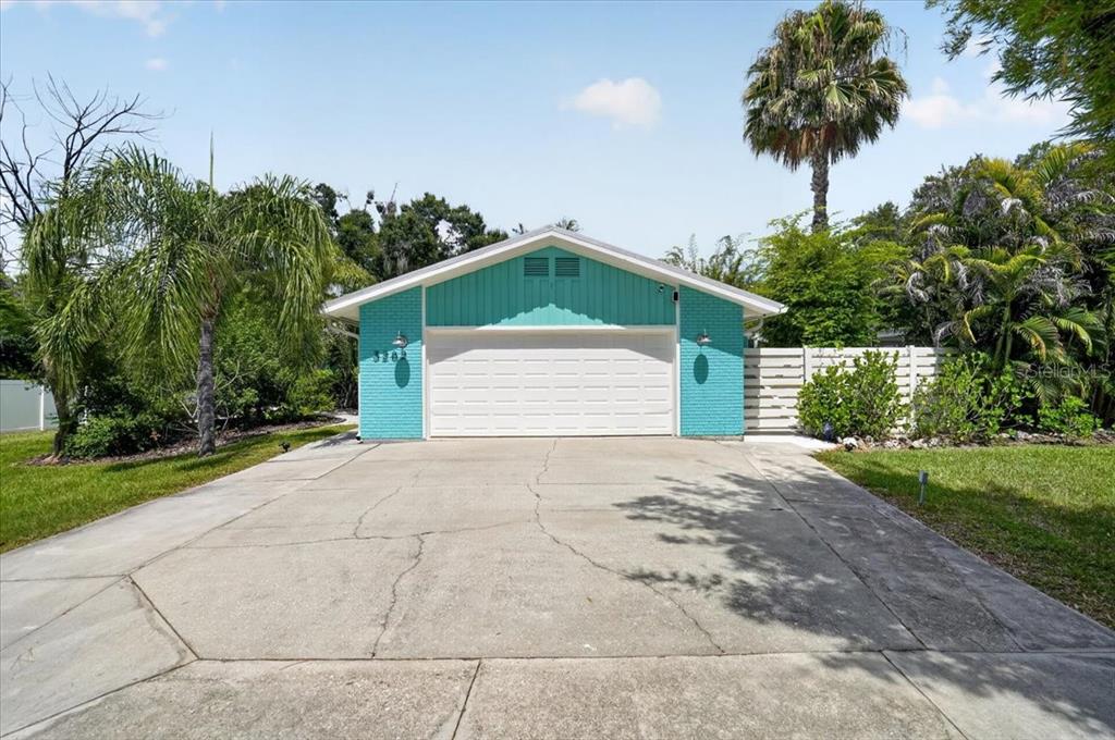 A detached garage with turquoise brick walls and a white garage door sits on a driveway — 3282 TOBERO LANE, SARASOTA, FL