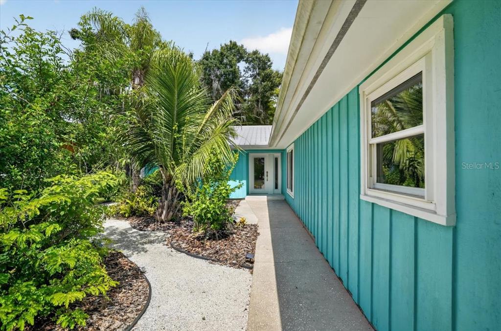 A turquoise house exterior features vertical siding, a white-framed window, and a concrete walkway — 3282 TOBERO LANE, SARASOTA, FL