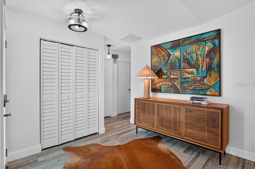 A foyer features a wooden sideboard, a cowhide rug, and a large abstract fish painting — 3282 TOBERO LANE, SARASOTA, FL