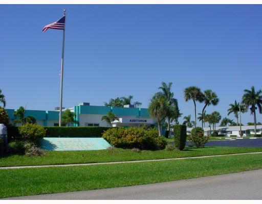 A teal and white auditorium building stands behind a grassy lawn with a flagpole — 2556 E Dudley Dr Drive E # D, West Palm Beach FL 33415, WEST PALM BEACH, FL