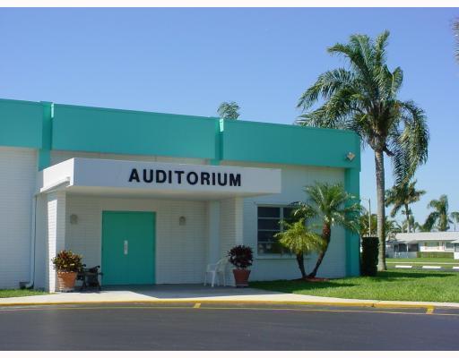 The exterior of a white and teal auditorium building features a covered entrance and palm trees — 2556 E Dudley Dr Drive E # D, West Palm Beach FL 33415, WEST PALM BEACH, FL