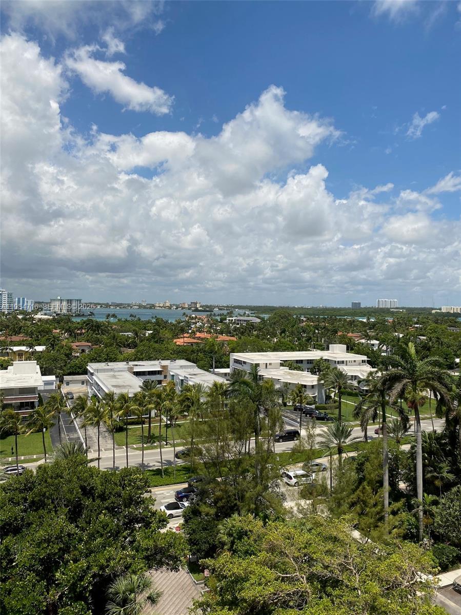 An elevated view of a tropical neighborhood with low-rise buildings, palm trees, and distant water — 10175 Collins Ave # 807, Bal Harbour FL 33154, BAL HARBOUR, FL