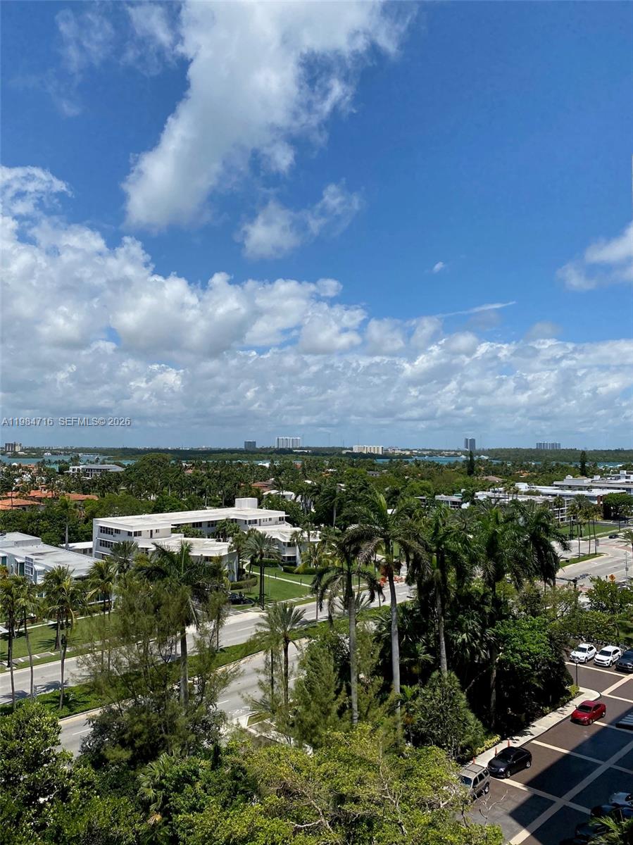 An elevated view of a tropical landscape with palm trees, white buildings, and distant water — 10175 Collins Ave # 807, Bal Harbour FL 33154, BAL HARBOUR, FL